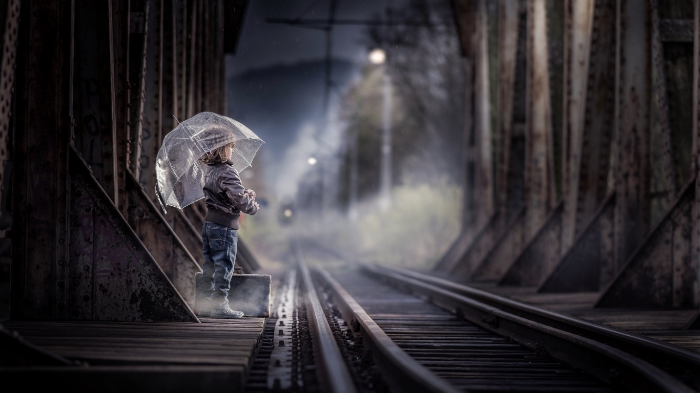 Ребенок под зонтом у железной дороги