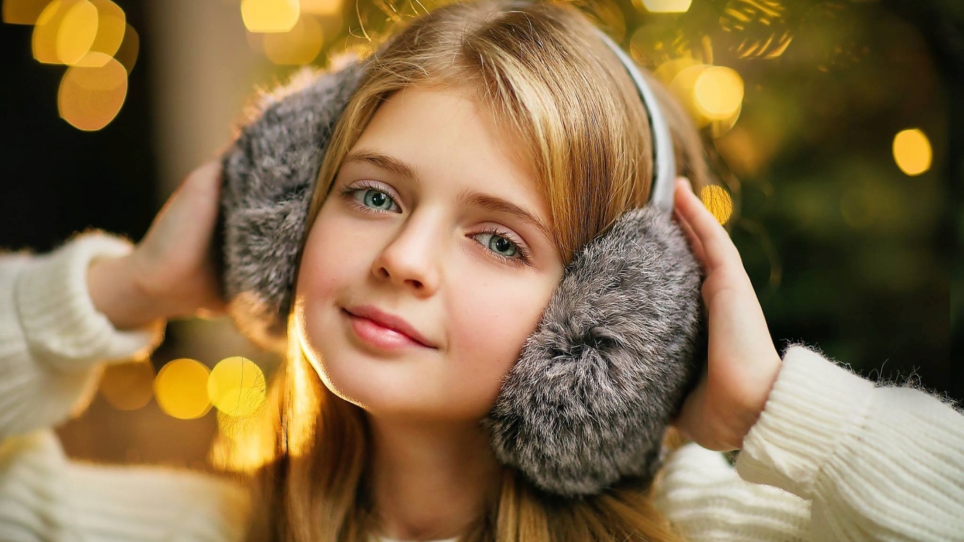 Красивая голубоглазая девочка в меховых наушниках