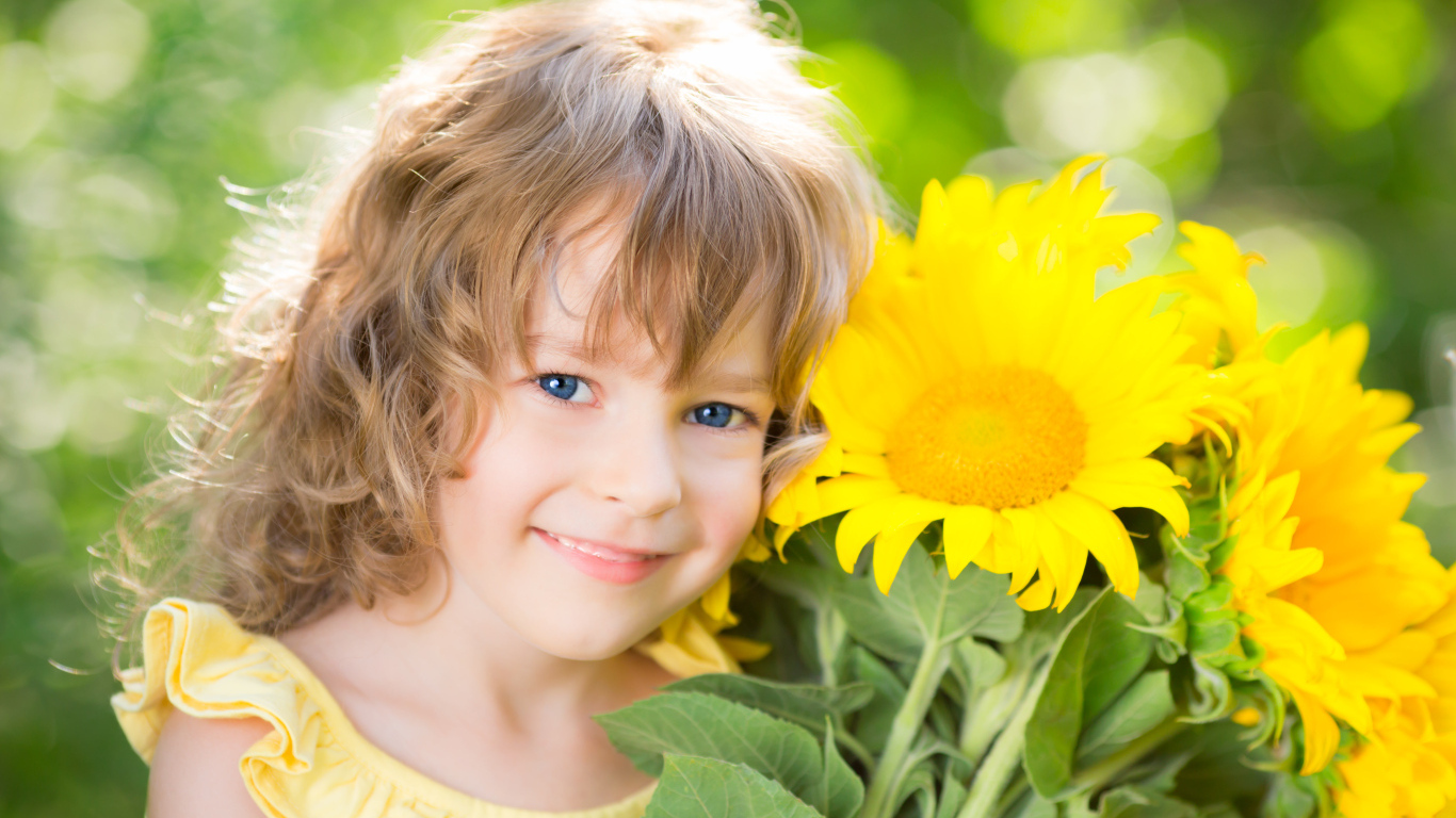 Красивая голубоглазая девочка с букетом подсолнухов