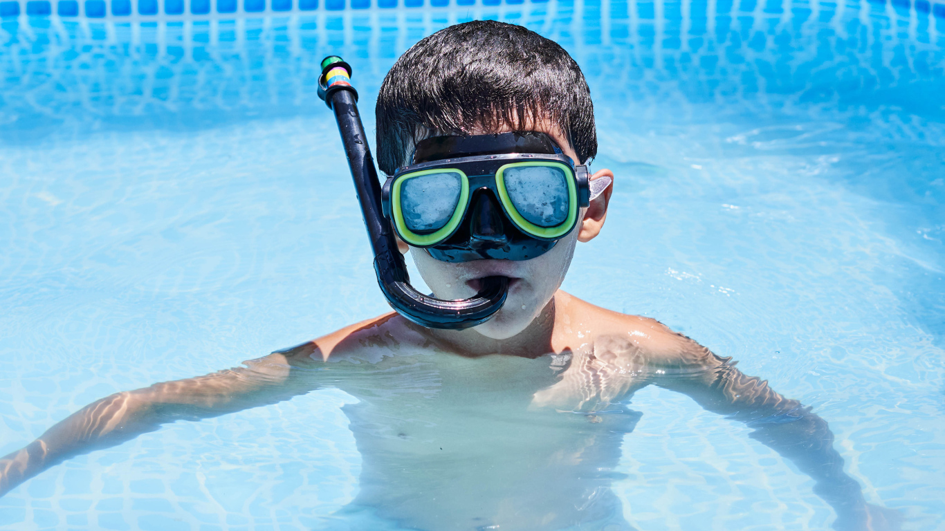 Мальчик в маске сидит в плавательном бассейне