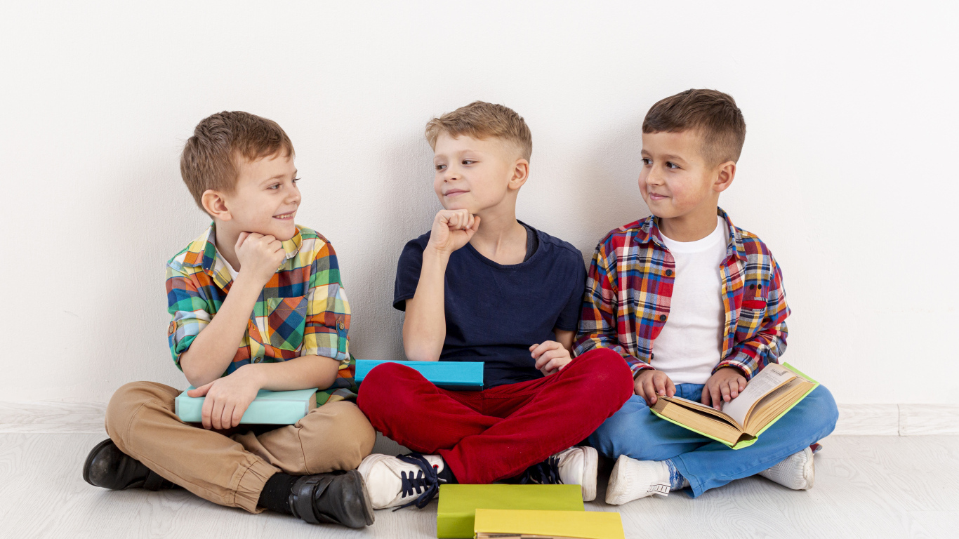 Три мальчика с книгами сидят у стены
