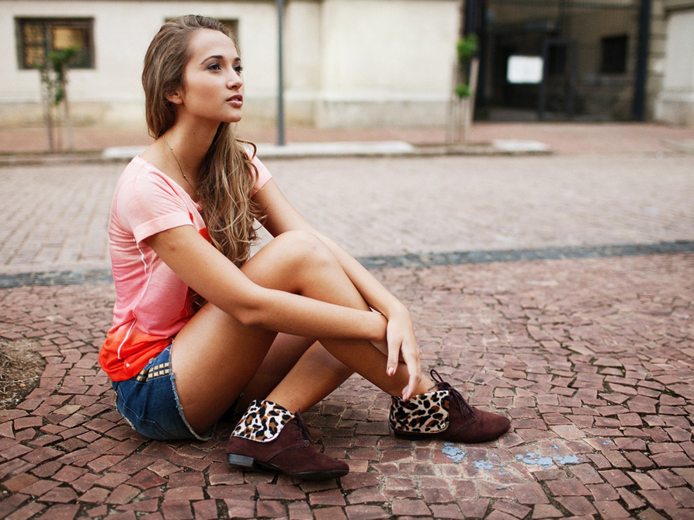 Брюнетка в шортах сидит на дороге