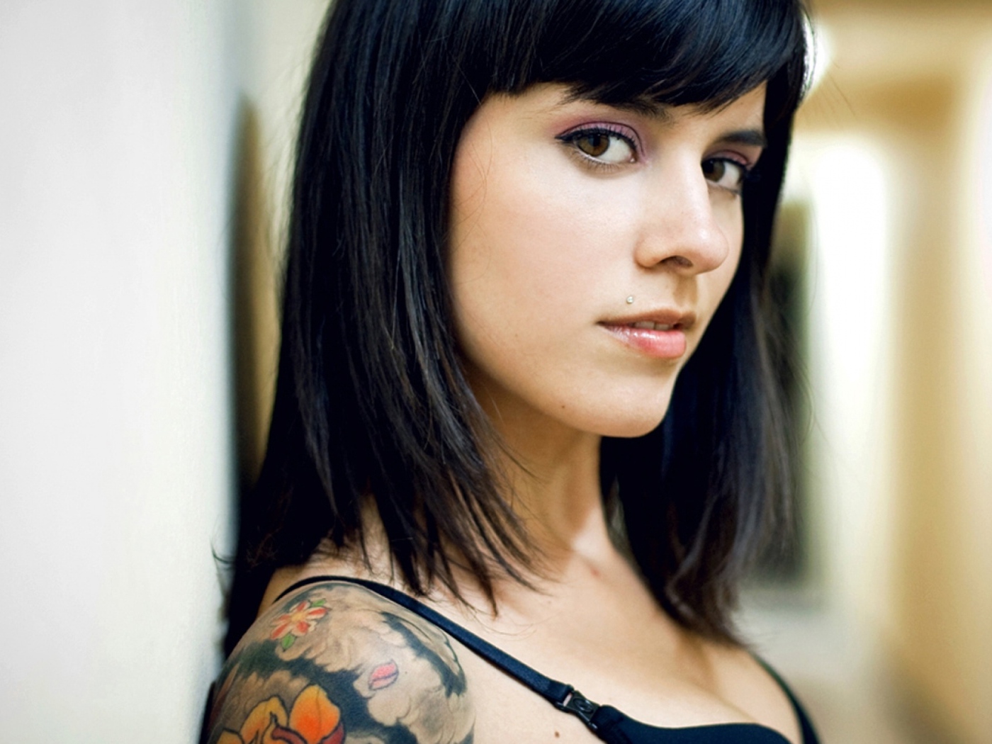 Девушка брюнетка с пирсингом в губе и татуировкой на плече