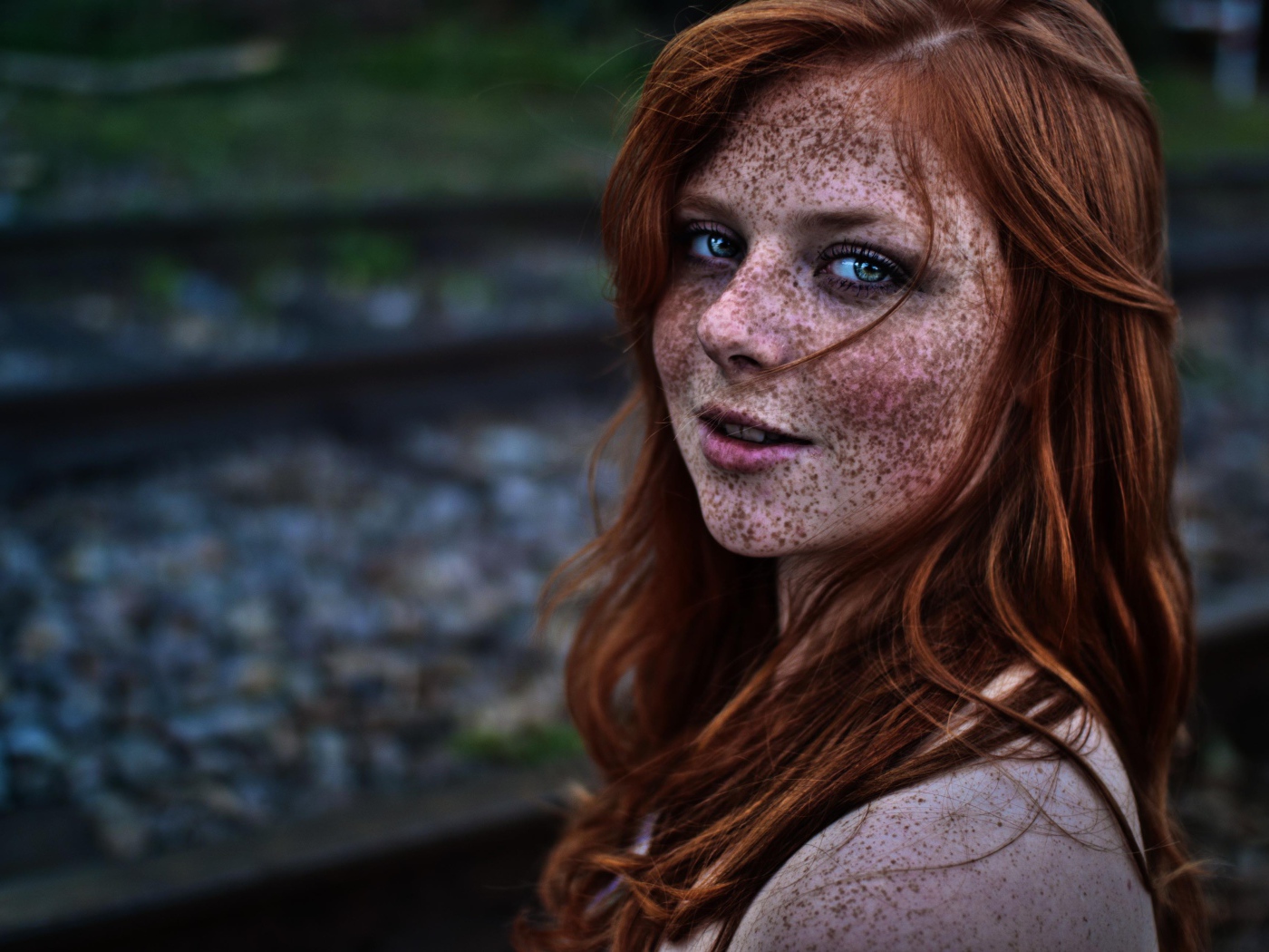 Девушка с веснушками на фоне рельс