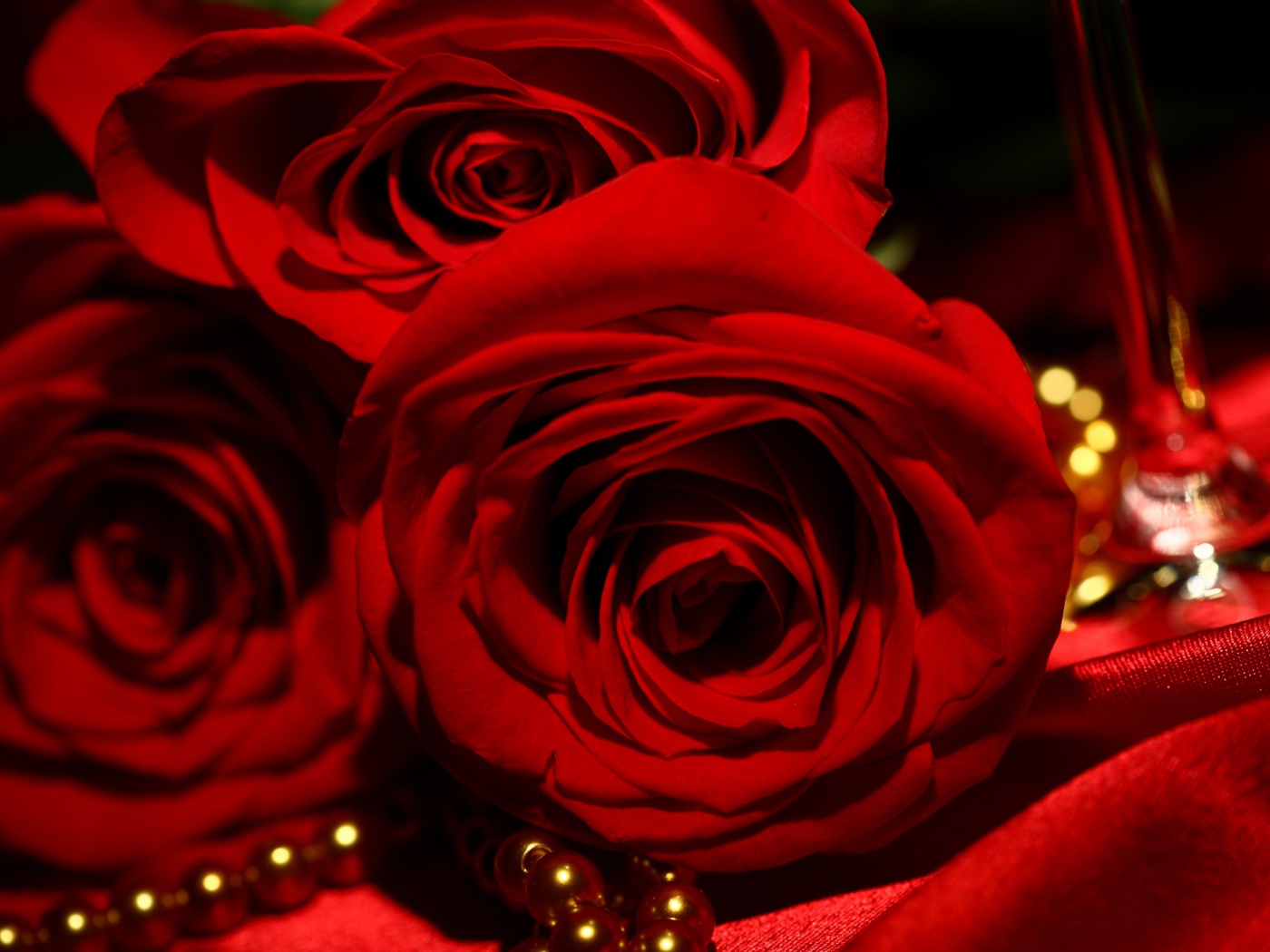 Красные розы на 8 марта на фоне атласа и жемчуга