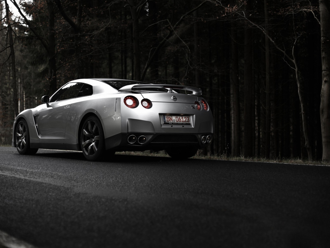 Серебристый Nissan GT-R на фоне темного леса