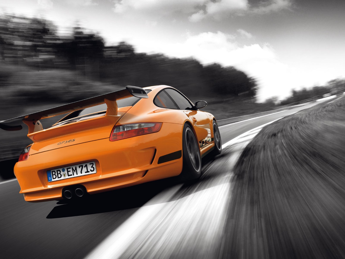 Оранжевый Porsche GT3RS на сером шоссе