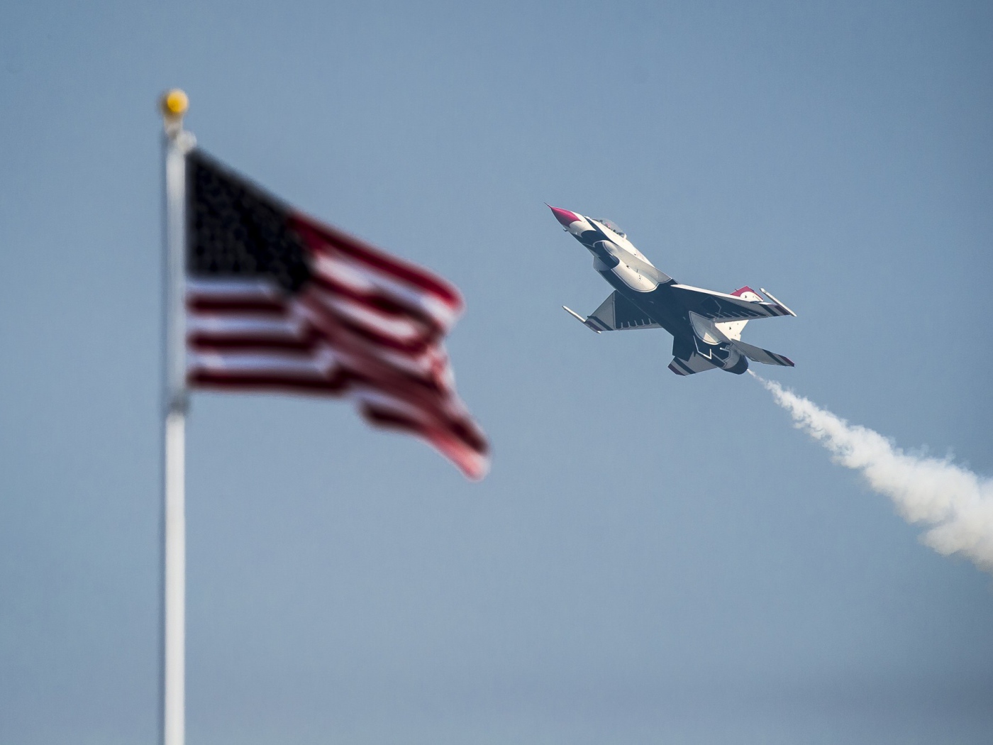 Истребитель F-16 Fighting Falcon пролетает над флагом США