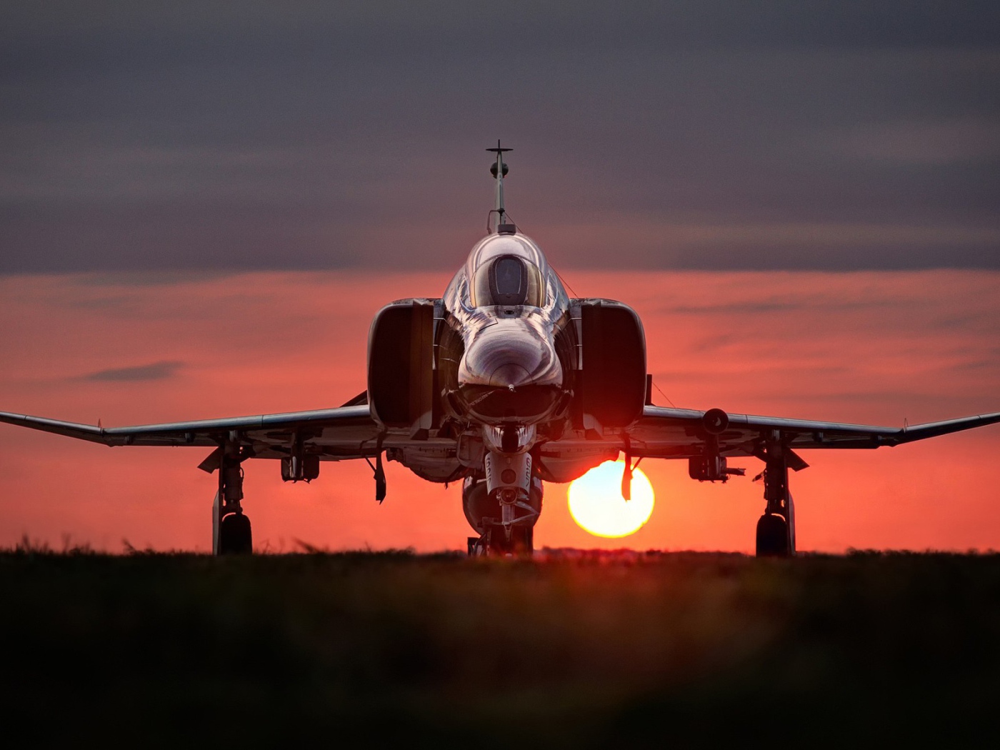 Истребитель F-4 Phantom II стоит на фоне заката