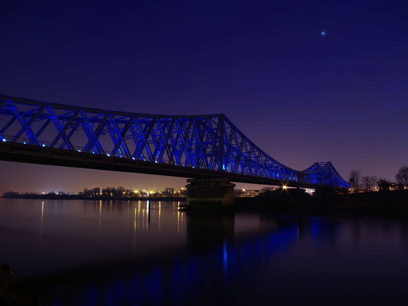Синяя ночная подсветка моста через реку