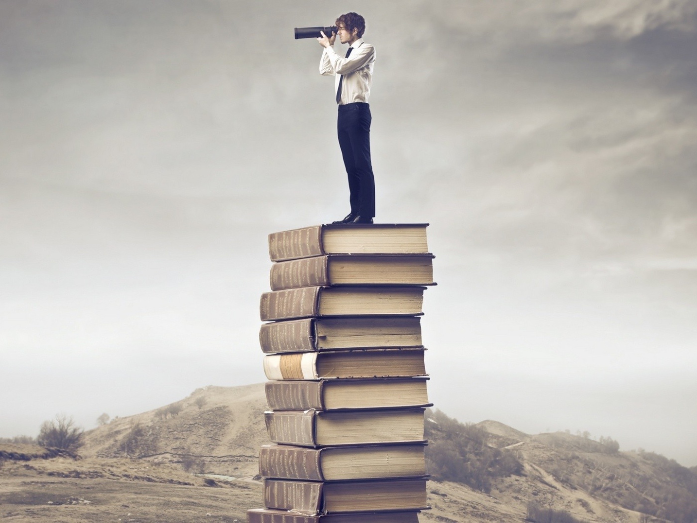 Мужчина с подзорной трубой на стопке книг