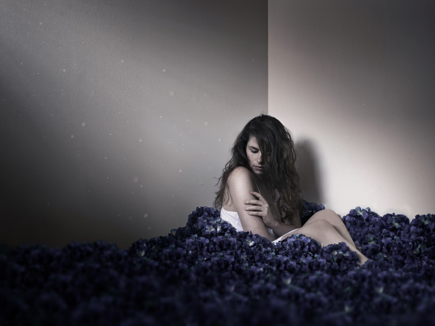 Девушка сидит в углу среди цветов