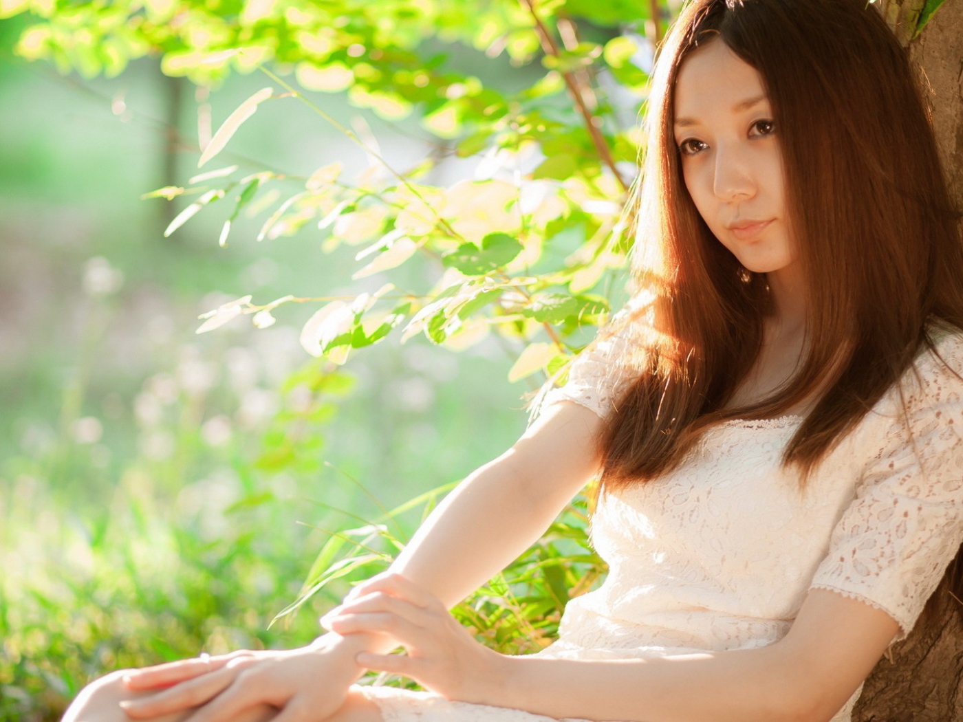 Азиатская девушка прислонилась спиной к дереву