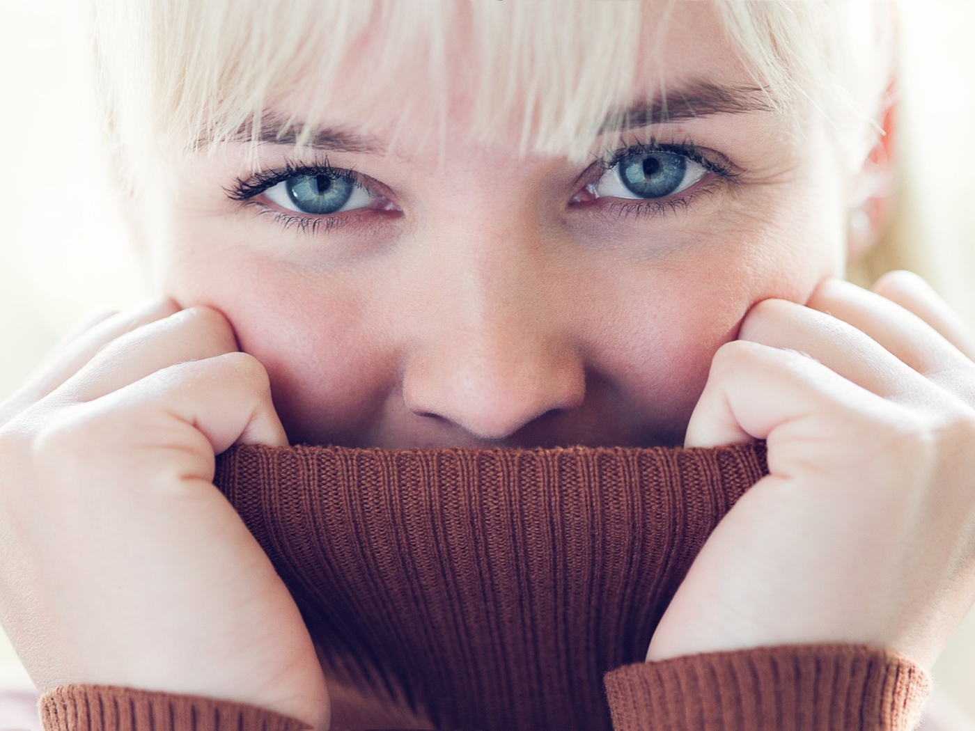 Блондинка прячет лицо в вороте свитера