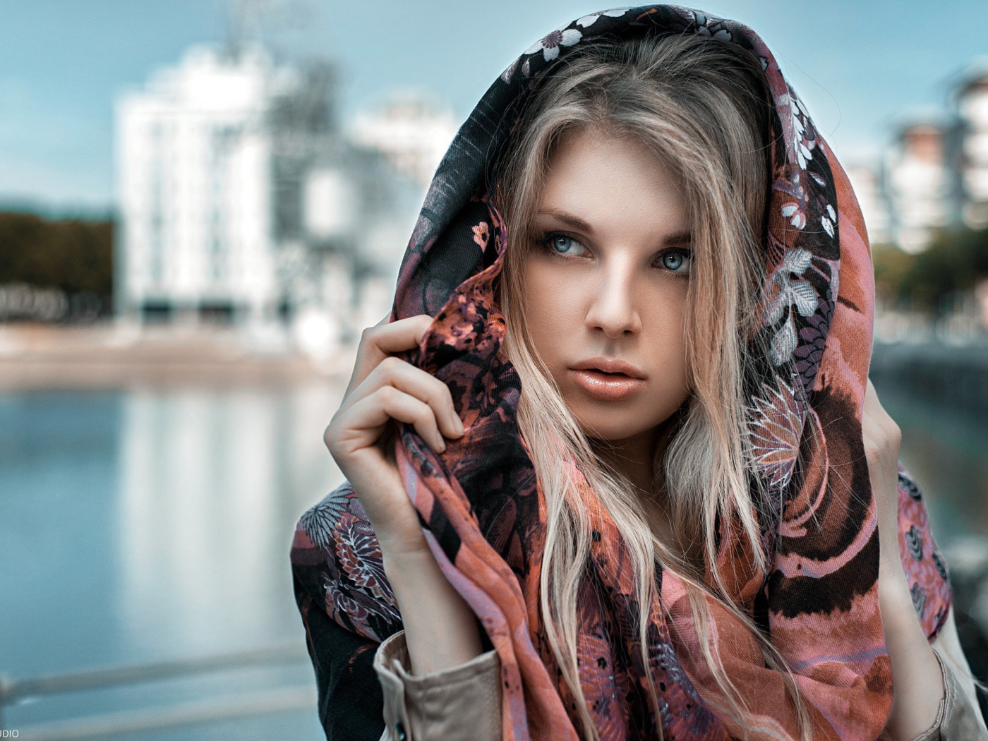 Блондинка в накидке на фоне городского пруда