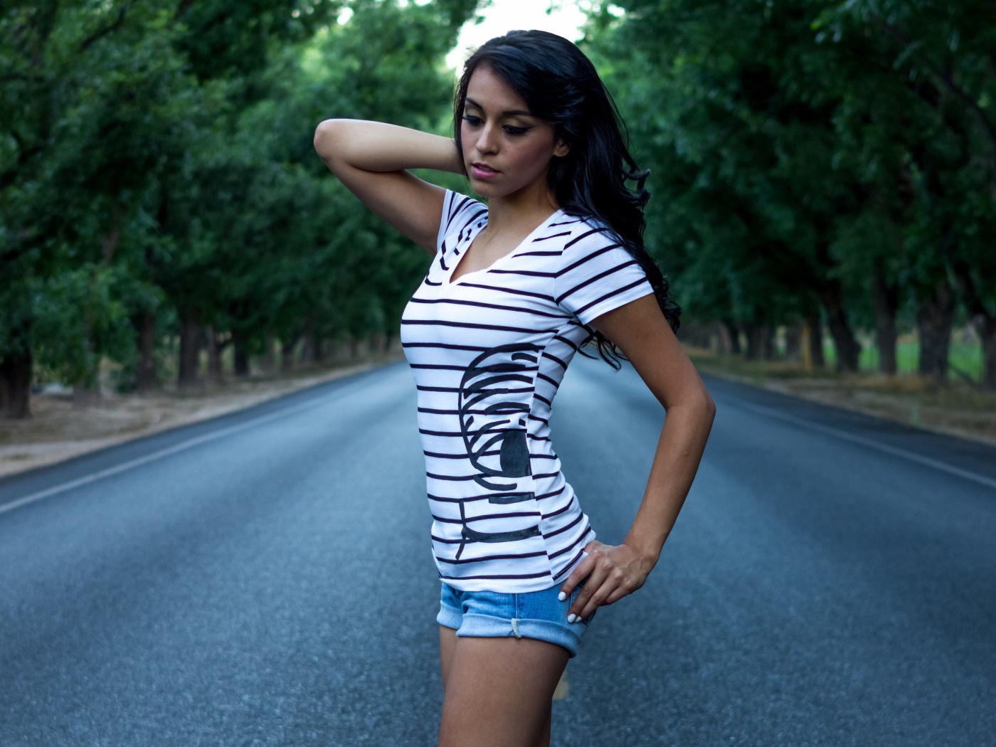 Брюнетка в джинсовых шортах среди дороги