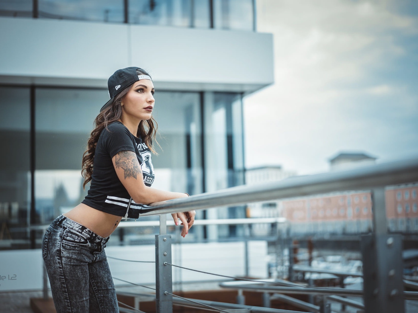 Девушка в кепке с тату смотрит на порт