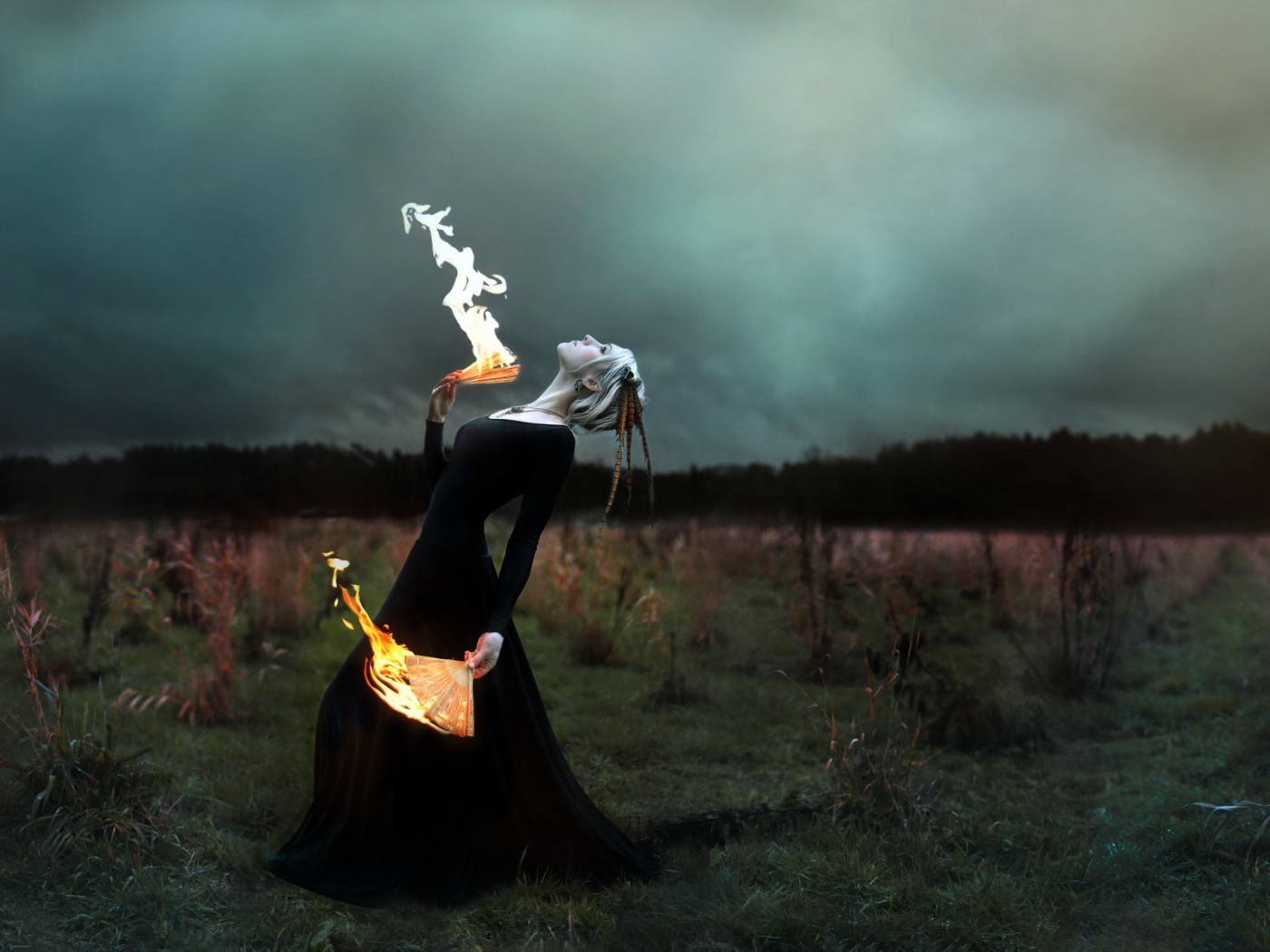 Девушка в черном платье играет с огнем