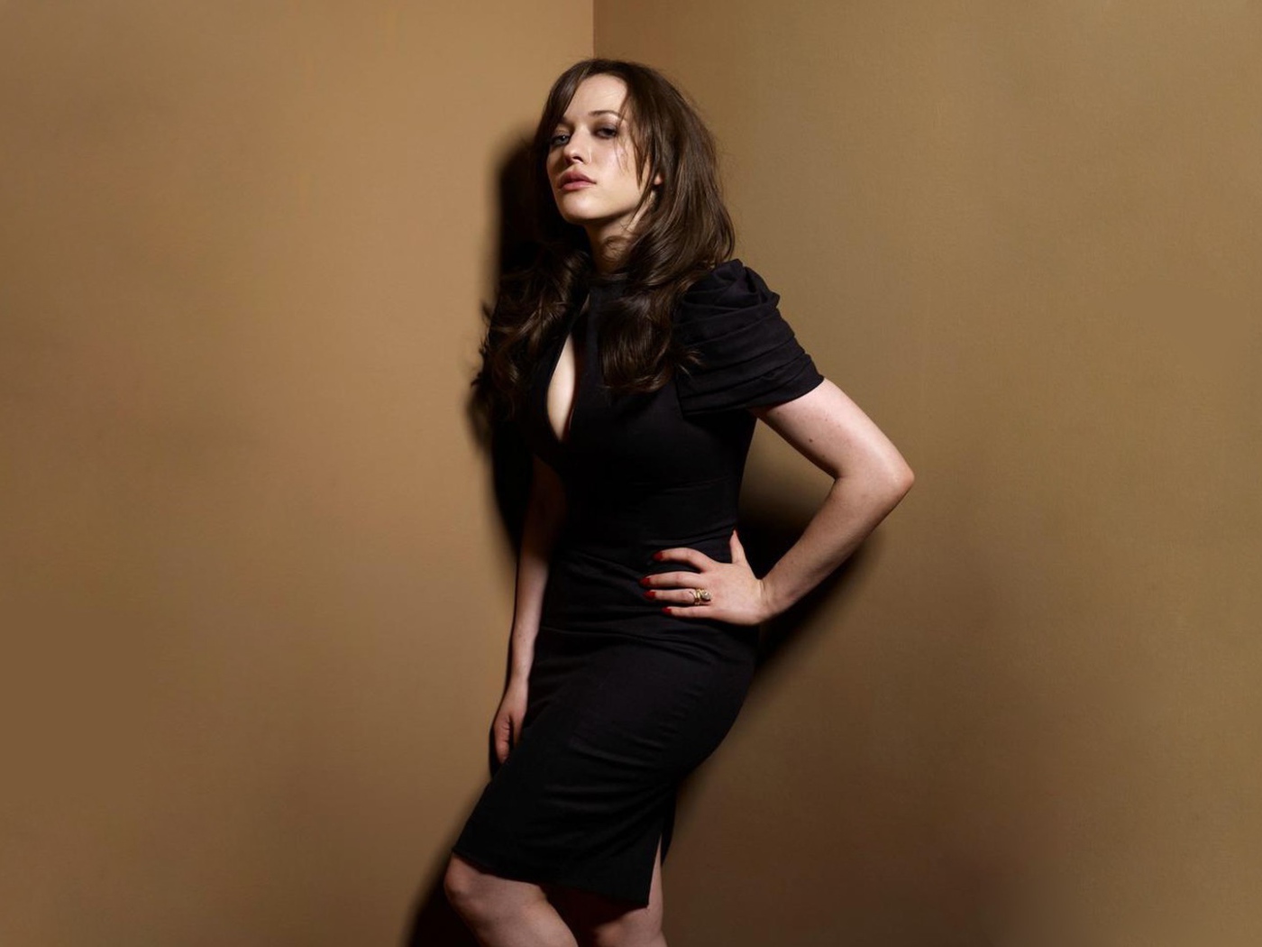 Девушка в черном платье стоит в углу