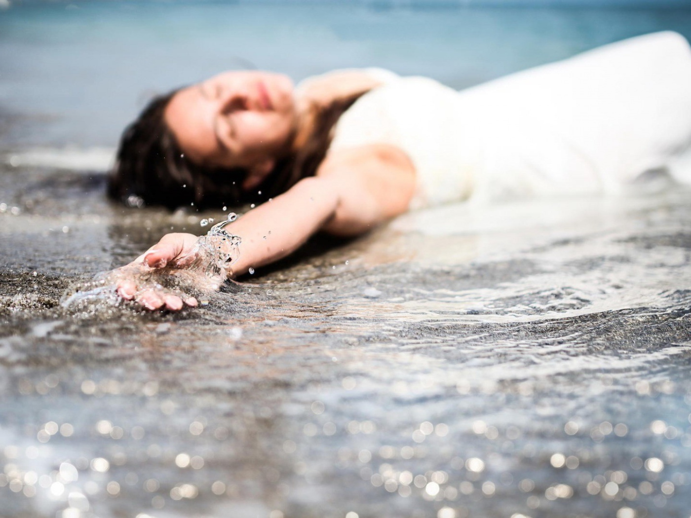 Девушка лежит в волне прибоя