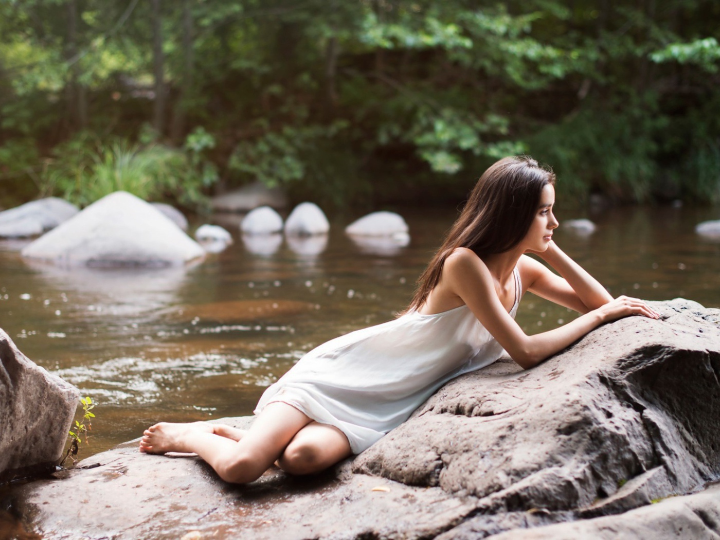 Девушка лежит на камне у реки
