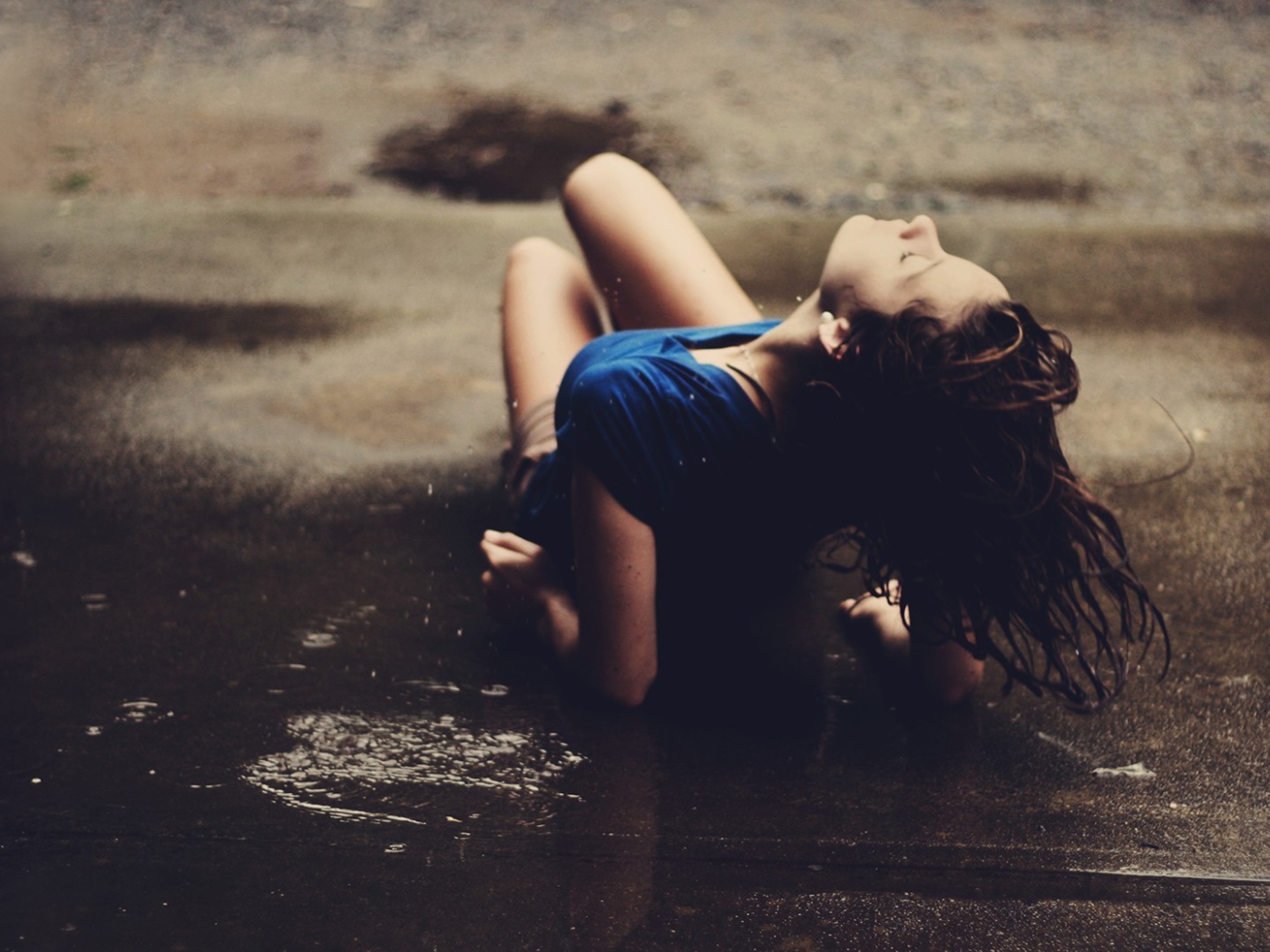 Девушка лежит на асфальте под дождем