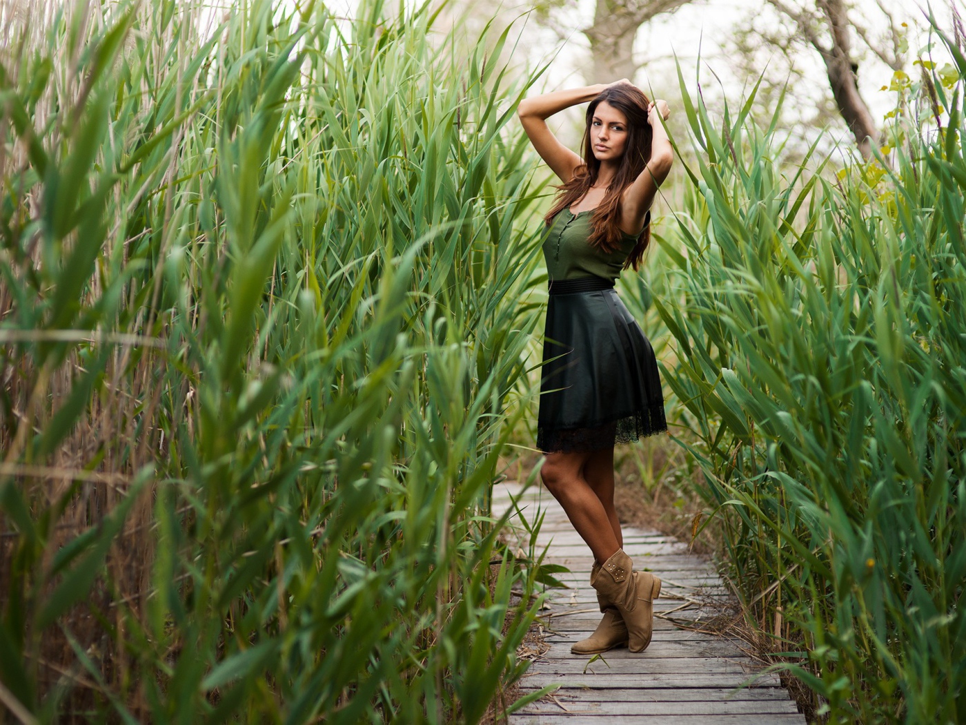 Девушка на деревянной дорожке среди камышей