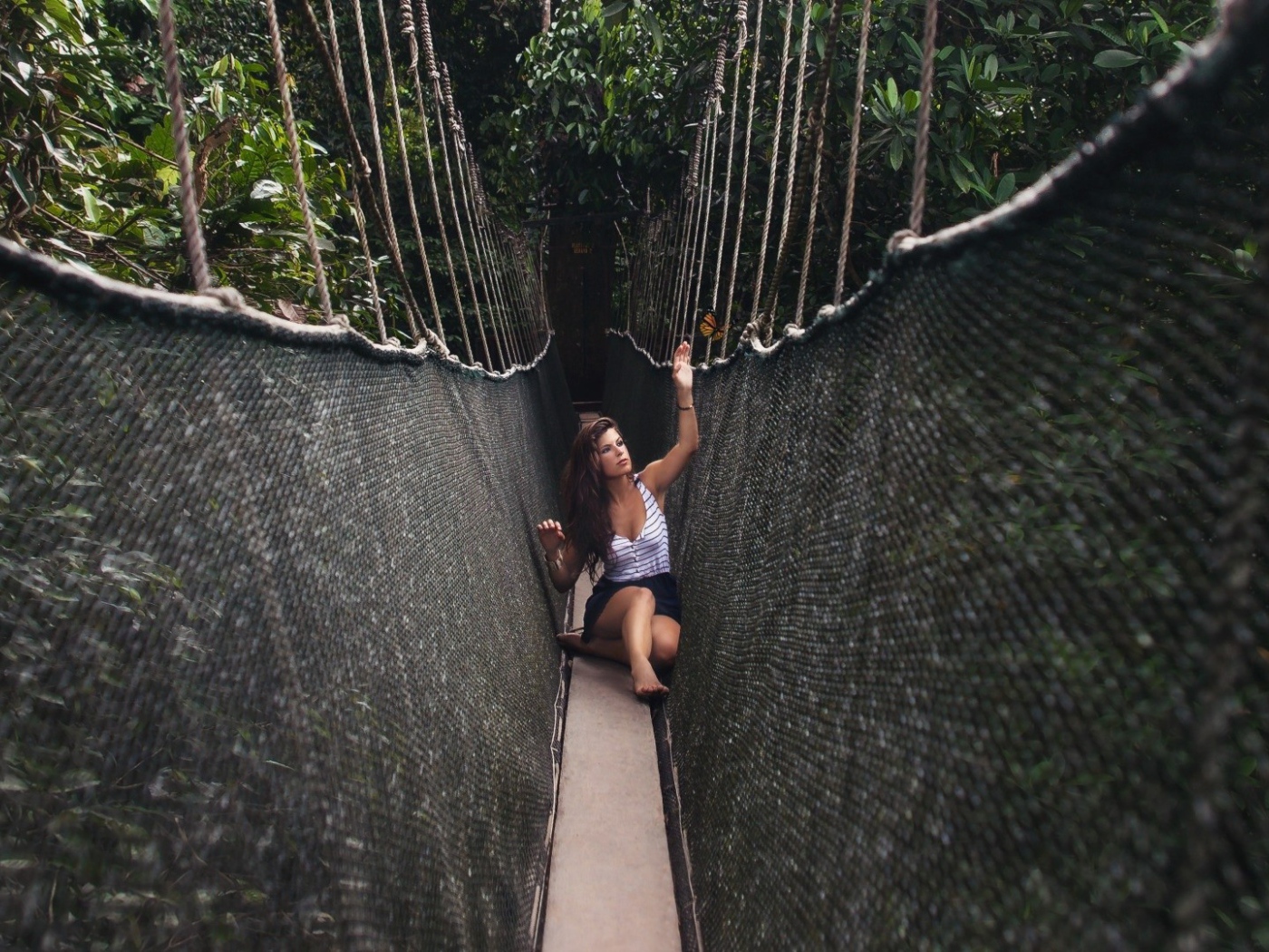 Девушка сидит на подвесном мосту