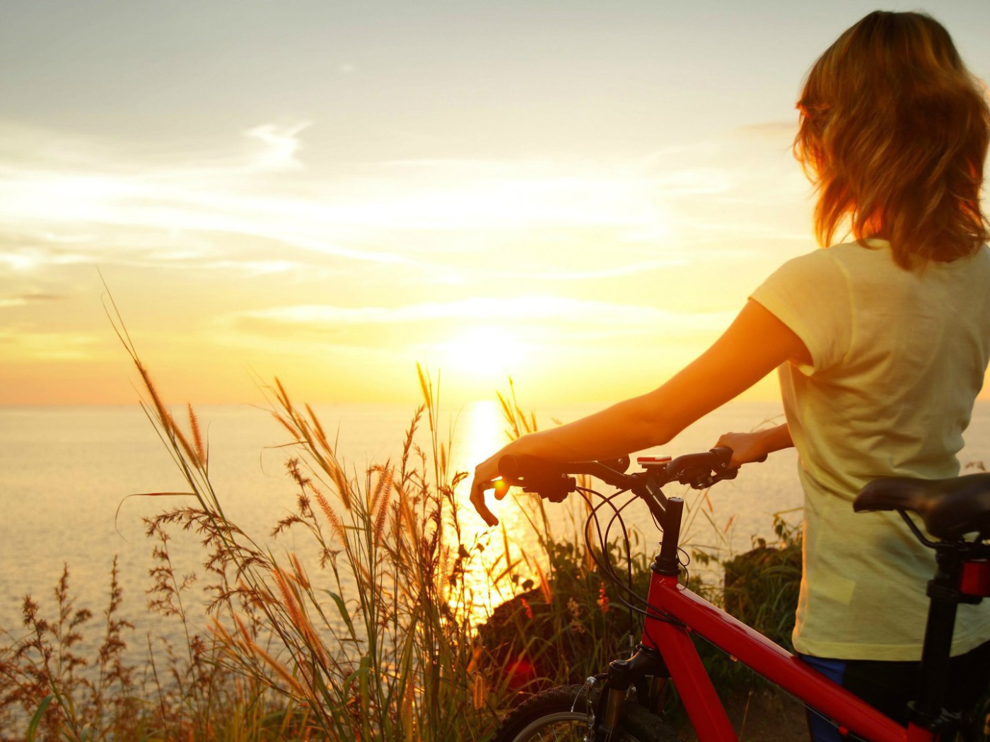 Девушка с велосипедом смотрит на закат