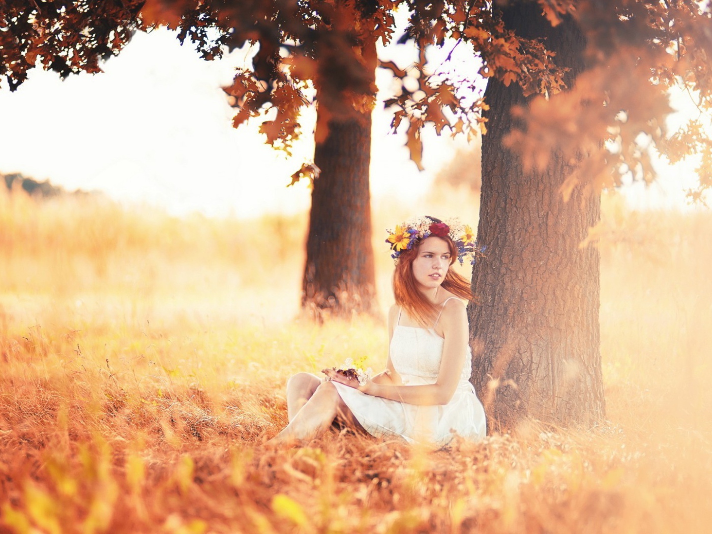 Девушка с венком на голове сидит под осенним деревом