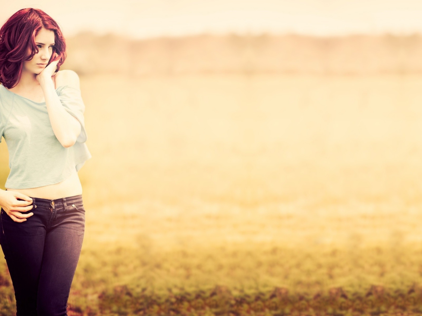 Рыжая девушка в джинсах и серой футболке