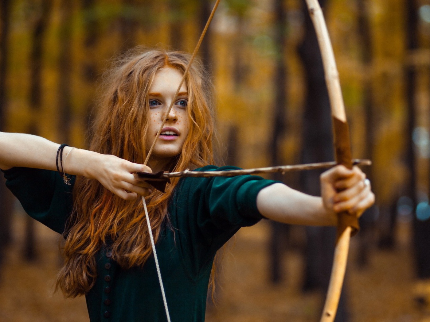 Рыжая девушка целится из лука