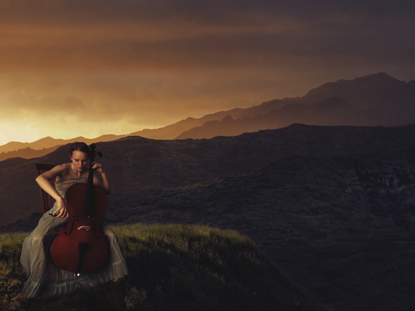 Девушка играет на виолончели на фоне гор