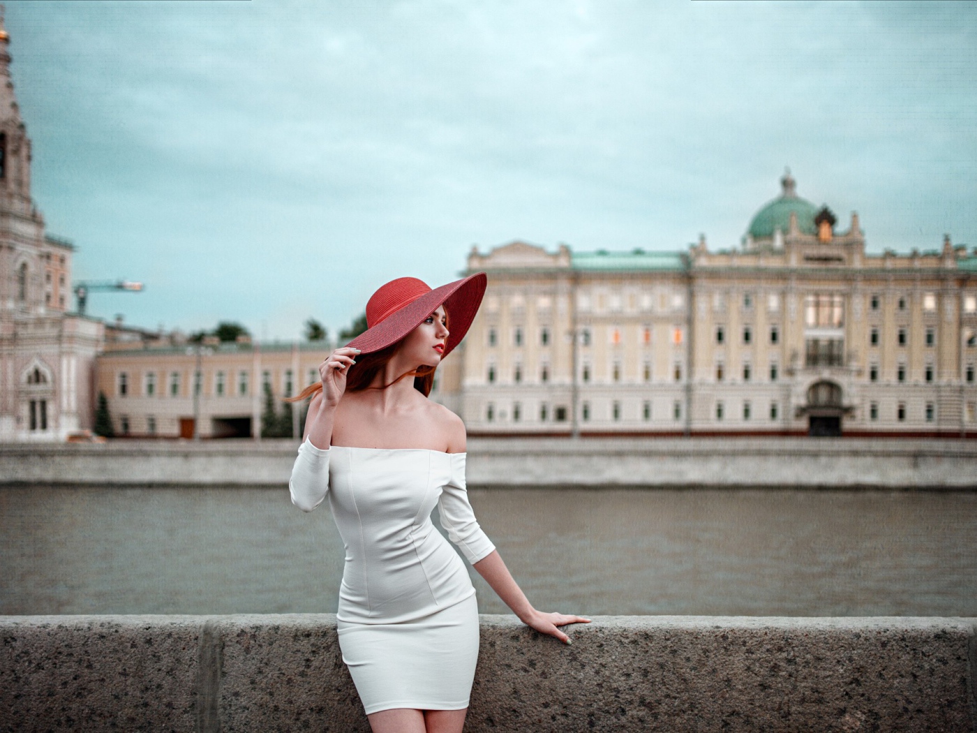 Девушка в белом платье и красной шляпе на набережной