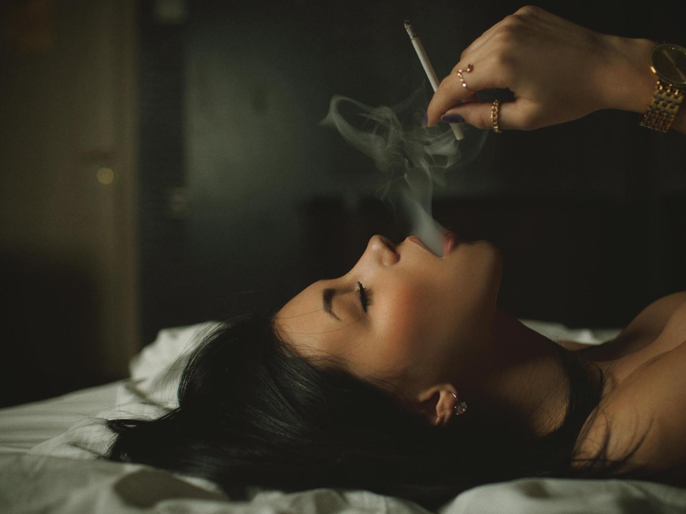 Девушка курит лежа в постели