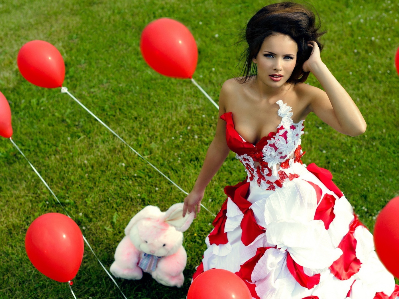 Девушка с игрушкой среди красных воздушных шариков