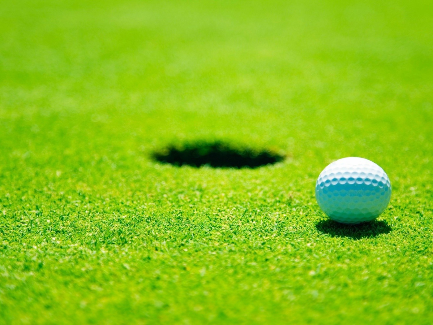 Белый мяч для гольфа у лунки
