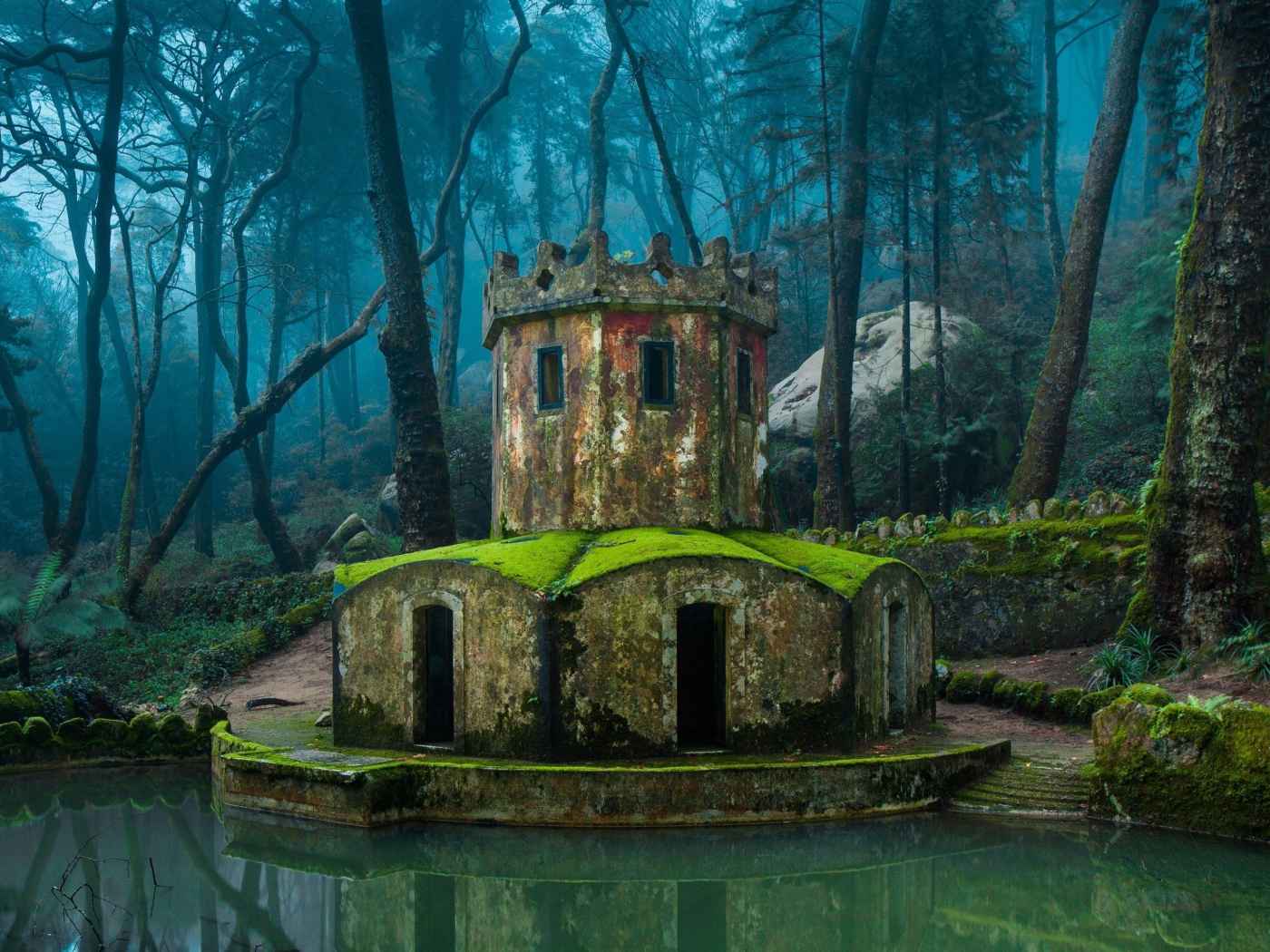 Покрытая мхом каменная беседка у воды