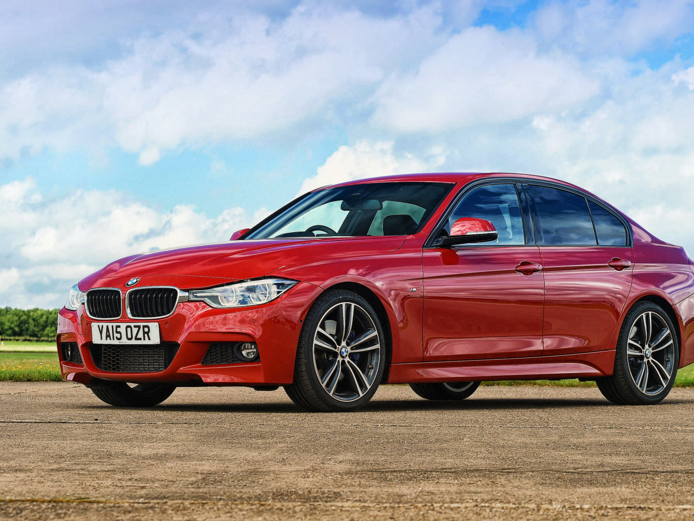 Стильный красный автомобиль BMW 3 Series на фоне неба 