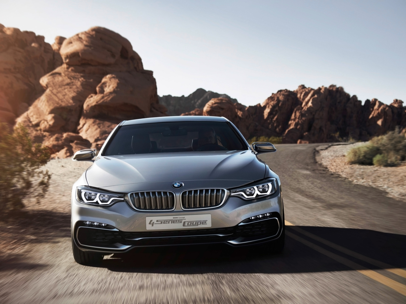 Серебристый автомобиль BMW 4 Series Coupe на дороге у скал