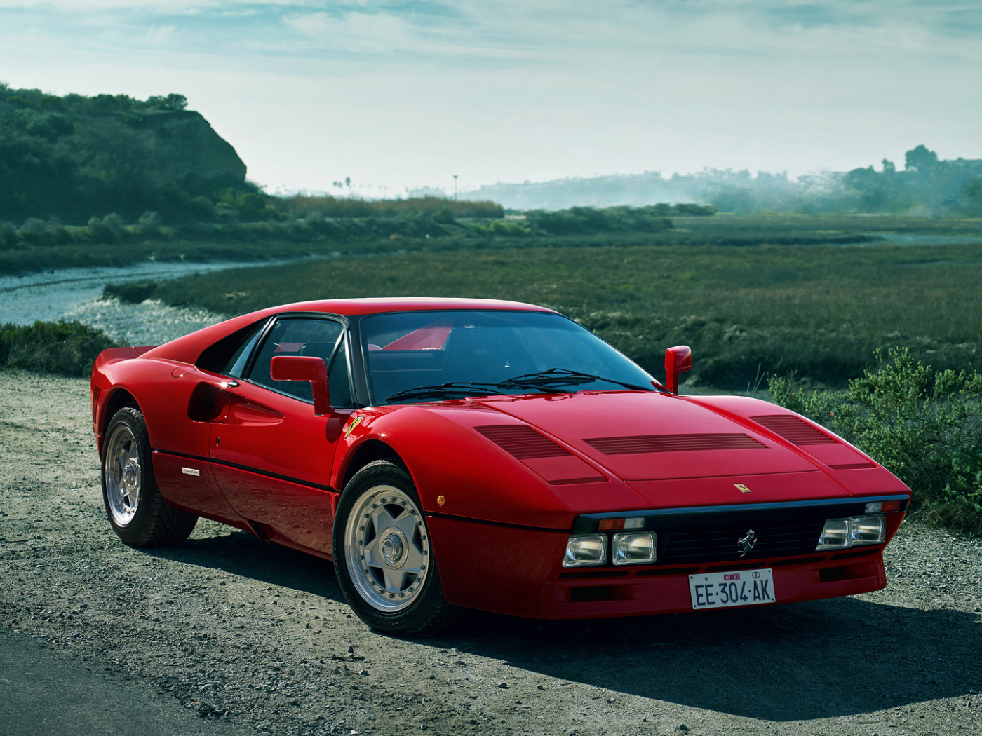 Красный быстрый автомобиль Ferrari 288 GTO у реки