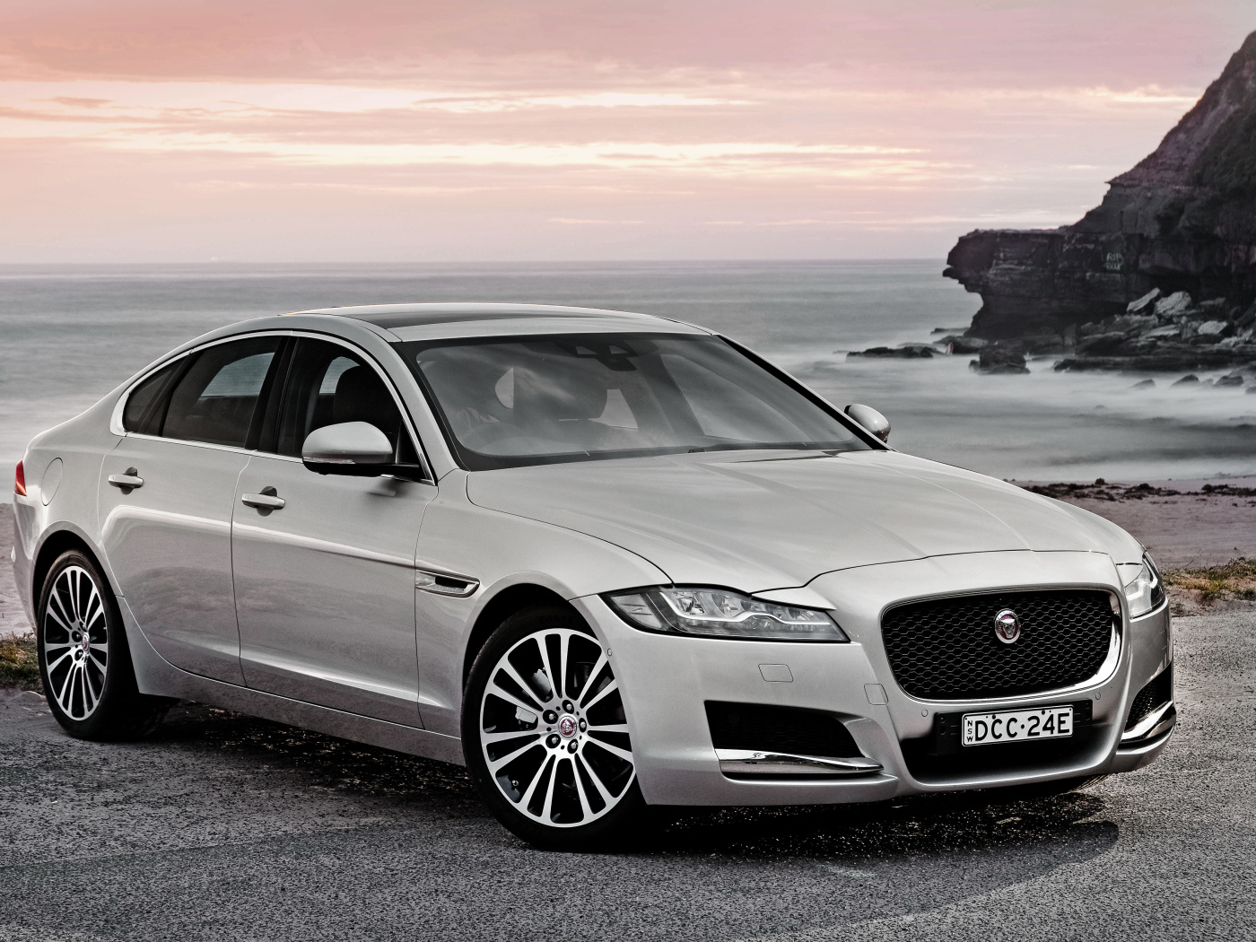 Серебристый автомобиль Jaguar XF на фоне океана