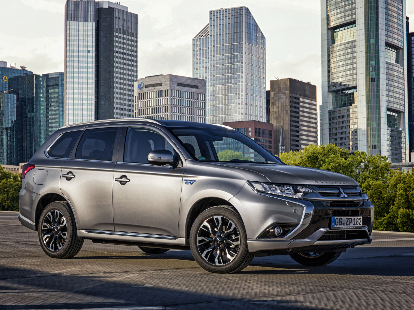Серебристый автомобиль Mitsubishi Outlander на фоне небоскребов 