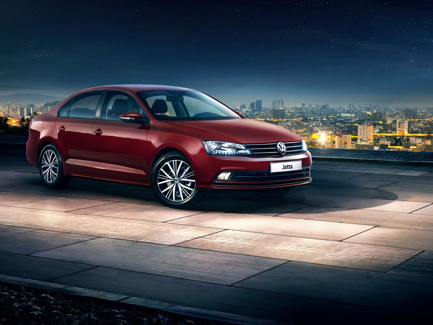 Красный автомобиль Volkswagen Jetta на фоне ночного города