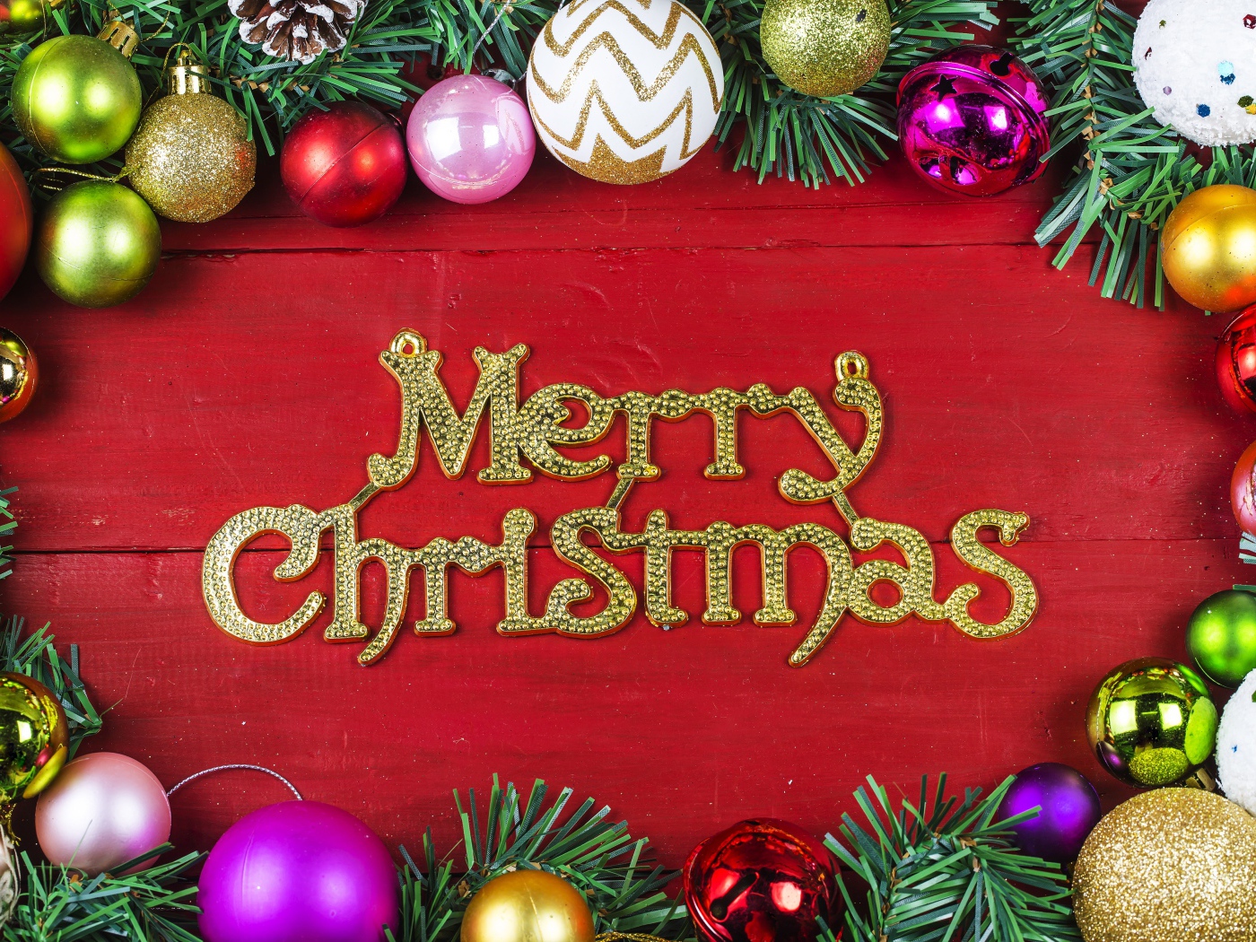Надпись Merry Christmas на красном фоне с елочными игрушками на Рождество