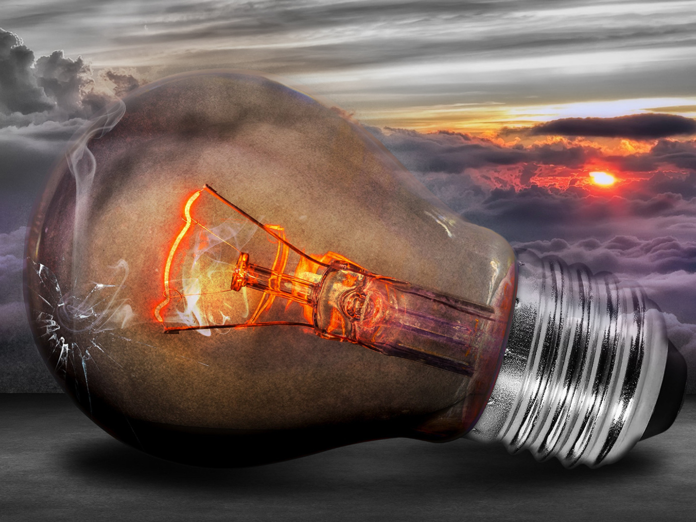 Раскаленная лампочка на фоне белых облаков в небе