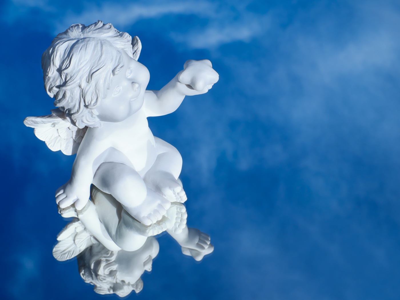 Маленькая статуя купидона отражается в голубой поверхности