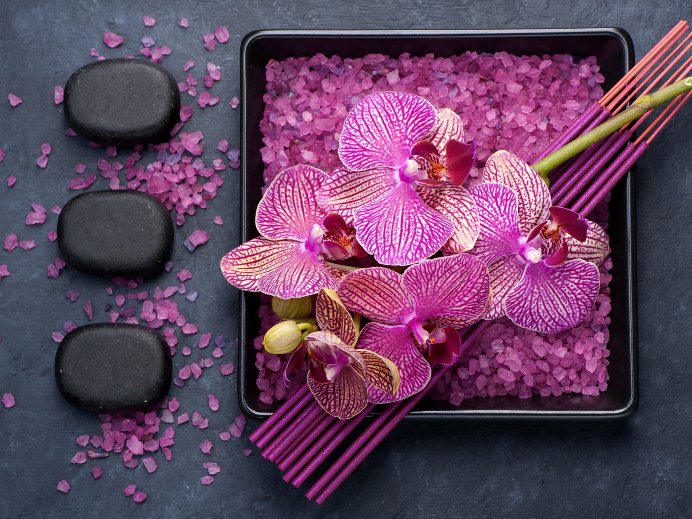 Цветы орхидеи с ароматическими палочками, камнями и солью