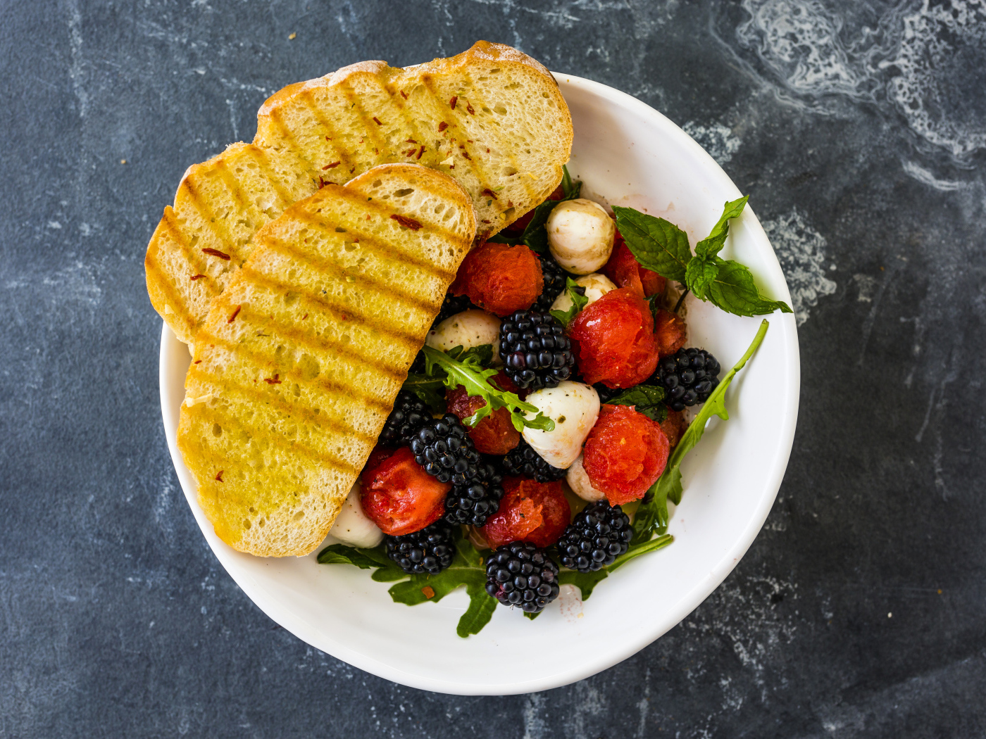 Гренки с салатом из ягод на белой тарелке