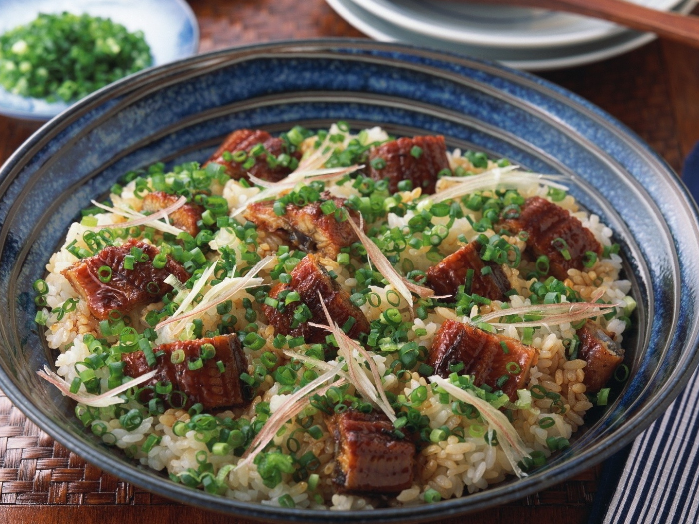 Рисовый плов с кусочками мяса и зеленым луком на столе